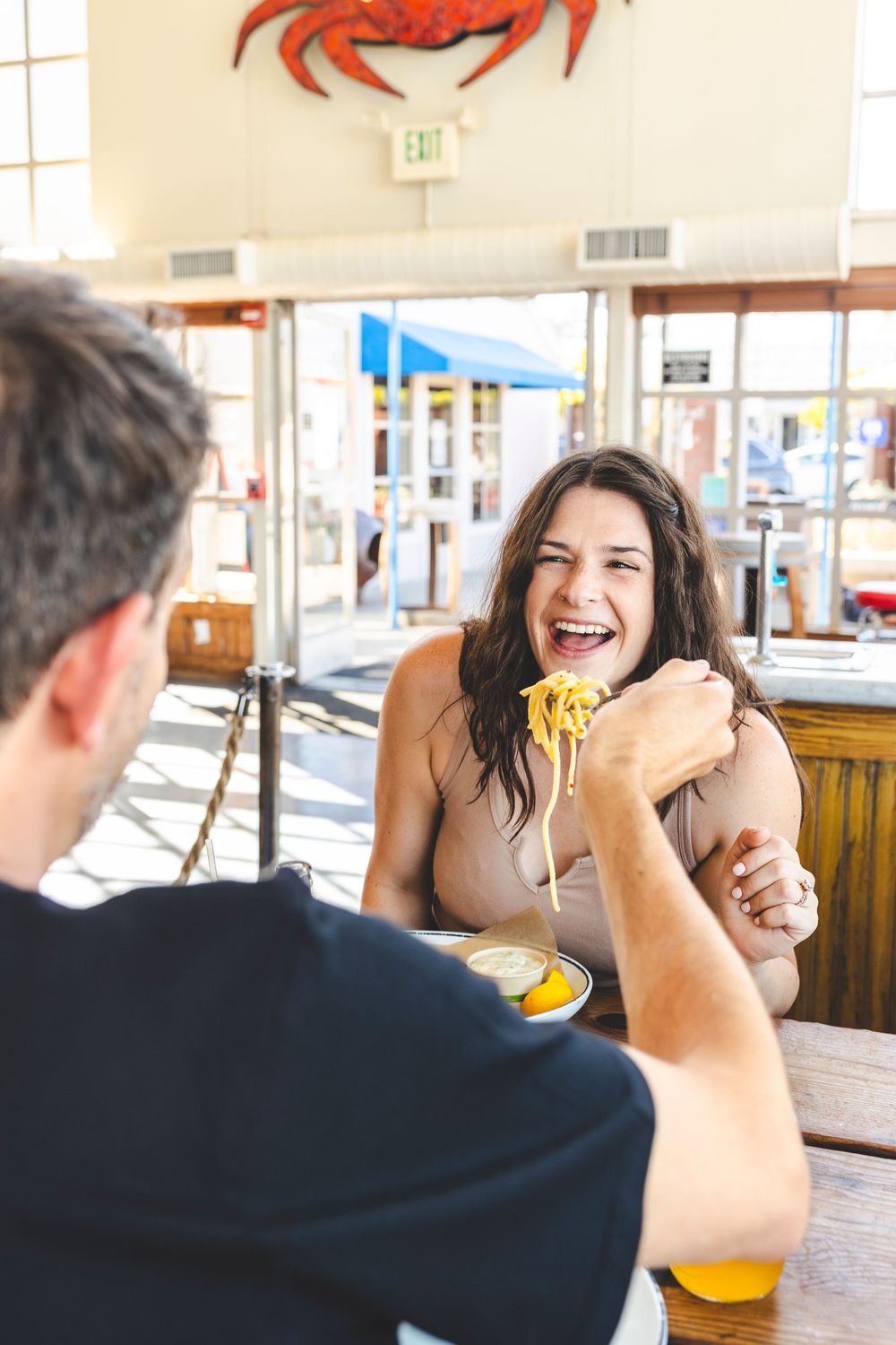 Two people sharing a meal at a casual restaurant with orange juice and pasta on the table.