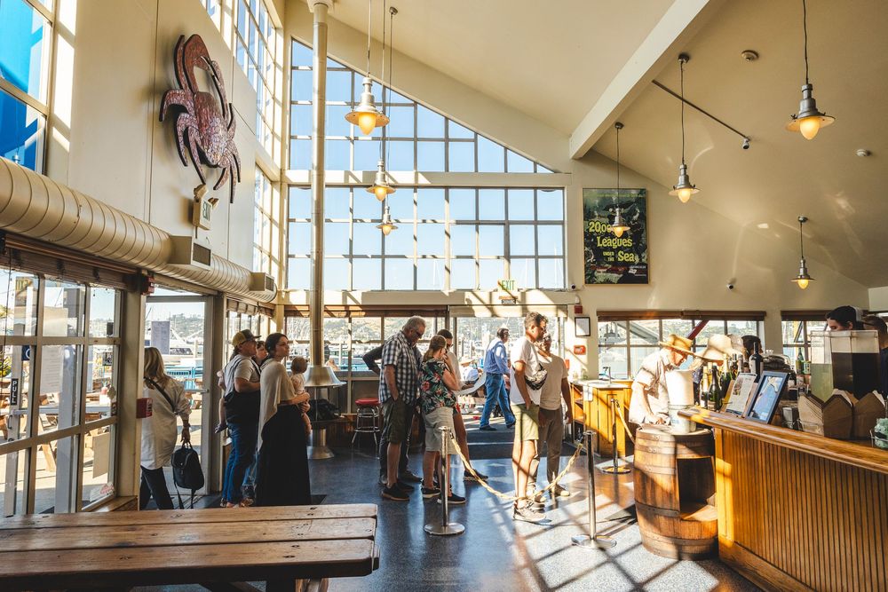 Bright restaurant interior with large windows, wooden tables and hanging pendant lights during daytime service.