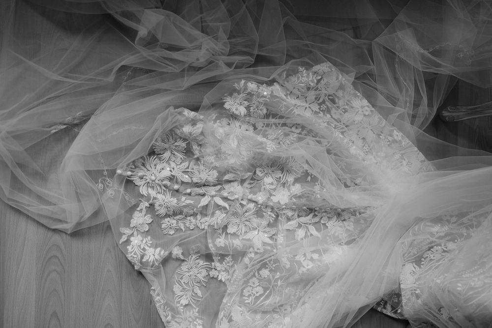 Close-up view of delicate lace and tulle fabric details from a white wedding dress.