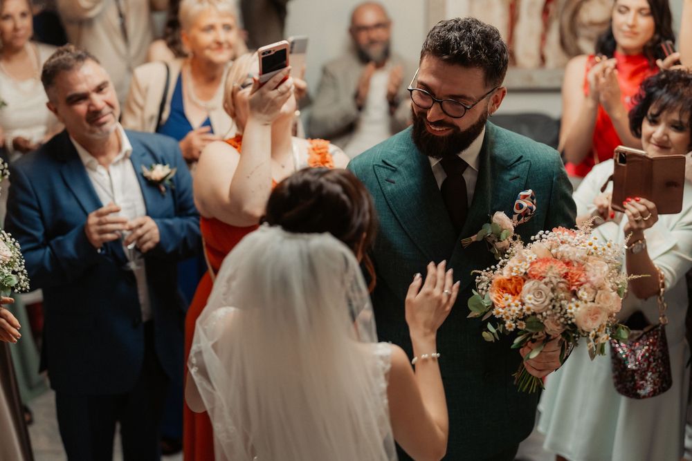 Guests gather at a wedding ceremony capturing candid moments and emotions with their smartphones and cameras.