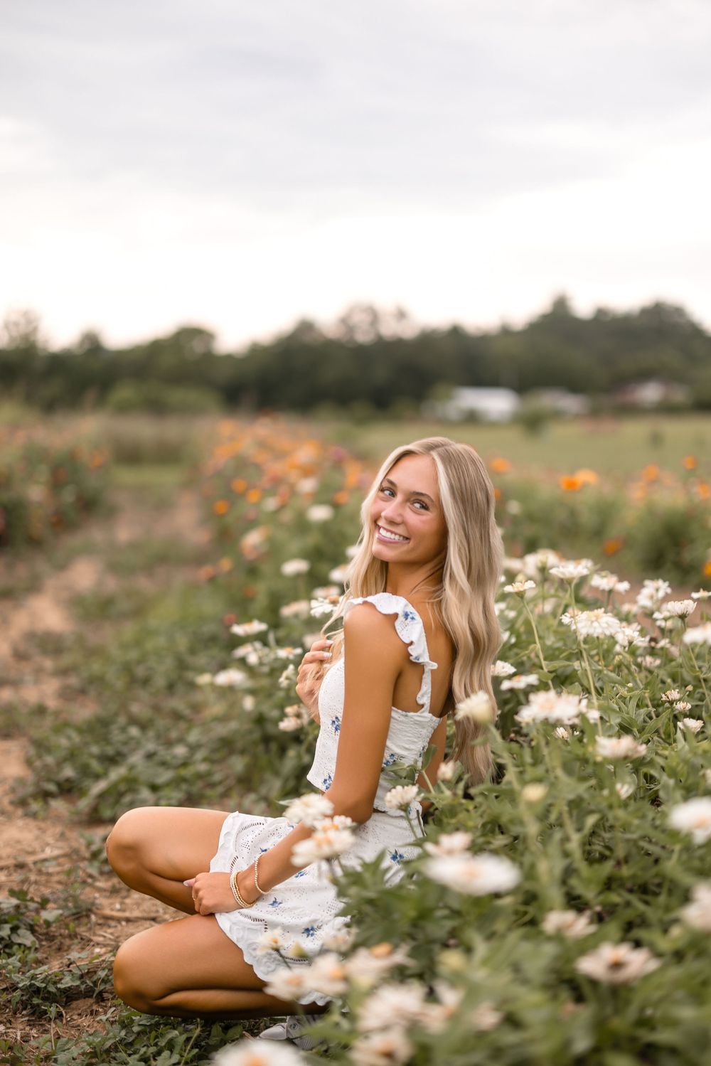 A scenic outdoor photoshoot featuring a white floral dress in a wildflower field during golden hour.