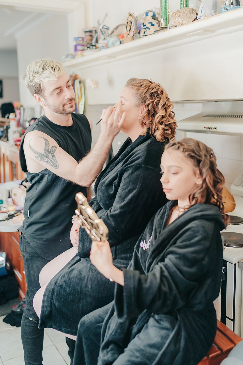Family members embrace and share emotional hugs in a light filled kitchen setting.