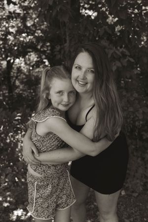 A tender black and white portrait showing a warm embrace against a natural outdoor backdrop.