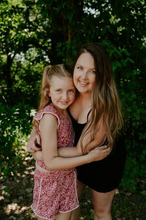 A joyful outdoor photoshoot featuring a loving embrace among green foliage.