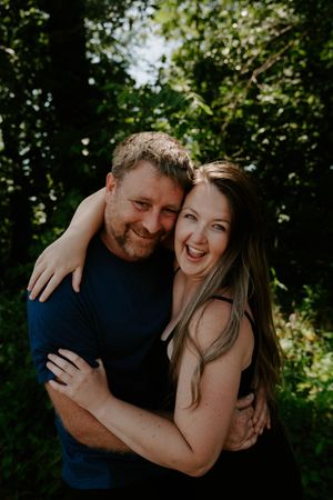 A joyful outdoor photo session showing genuine laughter and embraces among trees.