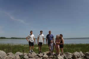People stand together on a scenic coastal landscape with blue water and sky.