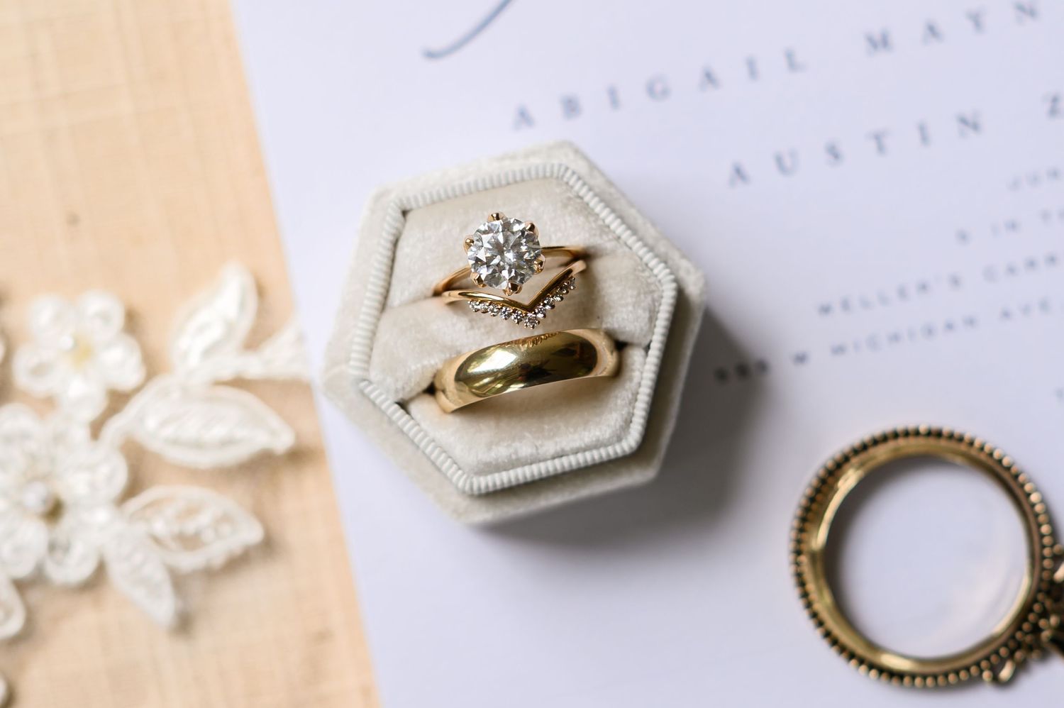 Vintage engagement ring and wedding band displayed on a cream velvet hexagonal ring box with lace detail.