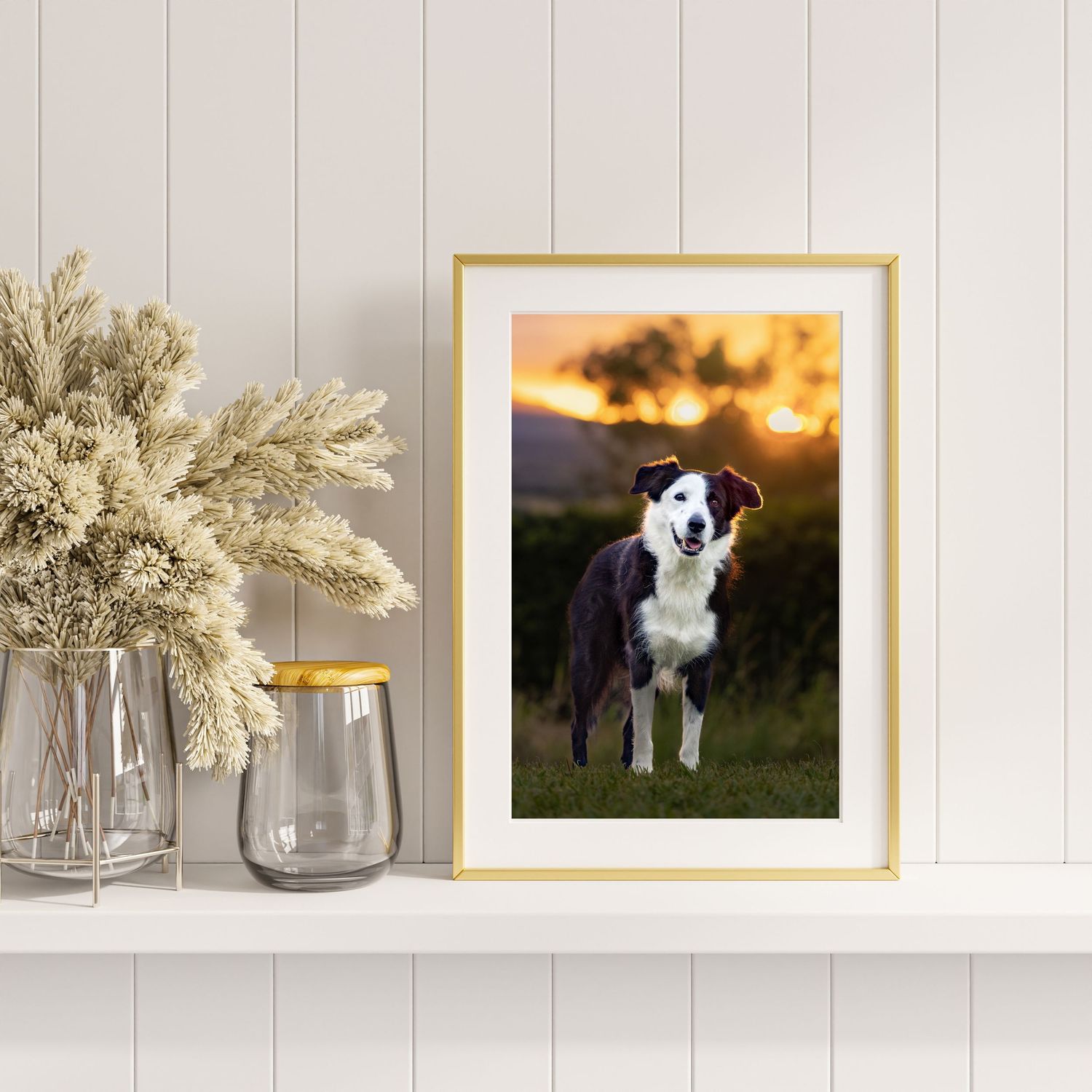 White shelving display with gold frames and dried floral arrangements.