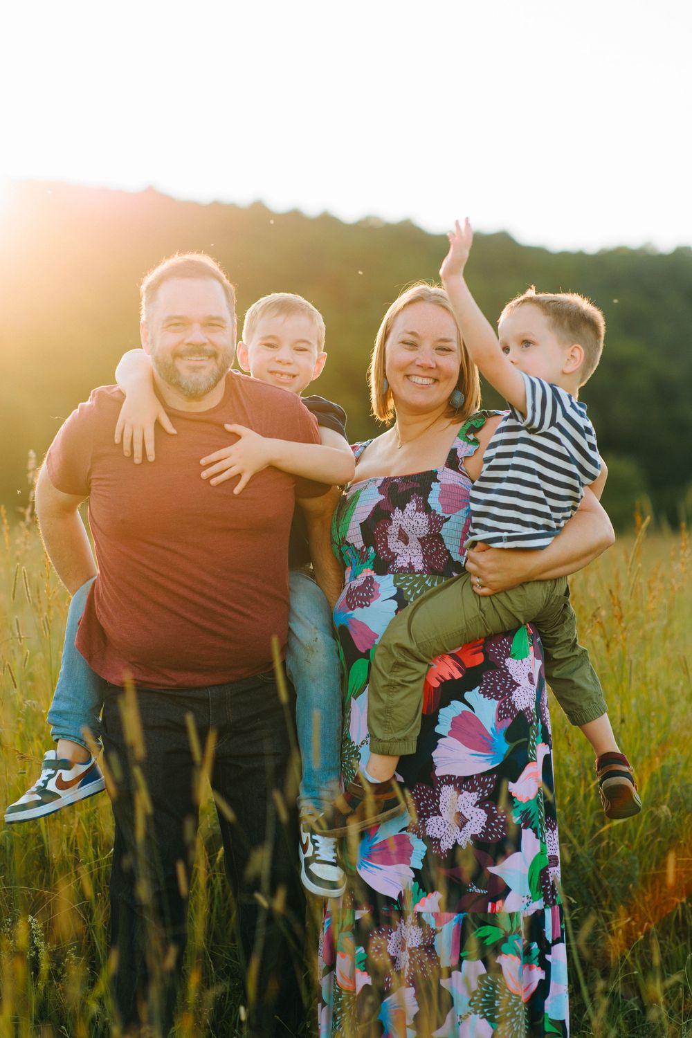 Family enjoying a beautiful sunset moment together in a golden wildflower meadow, with warm sunlight glowing behind them.
