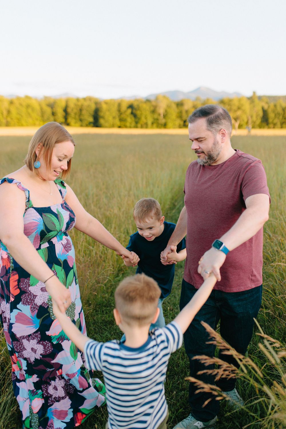 Family plays together in a golden wheat field during sunset at a rustic farm setting.