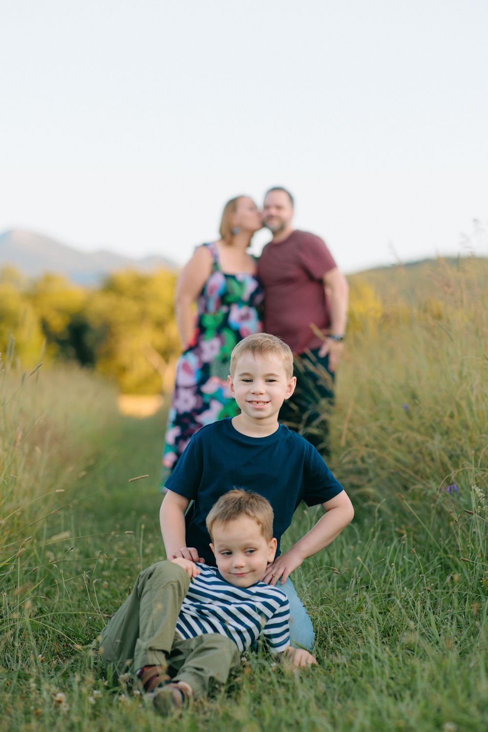 Family enjoying golden hour in a tall grass meadow during an outdoor photo session at sunset.