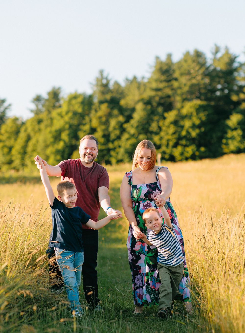 Family enjoying a playful moment together in a golden wheat field at sunset, running and laughing.