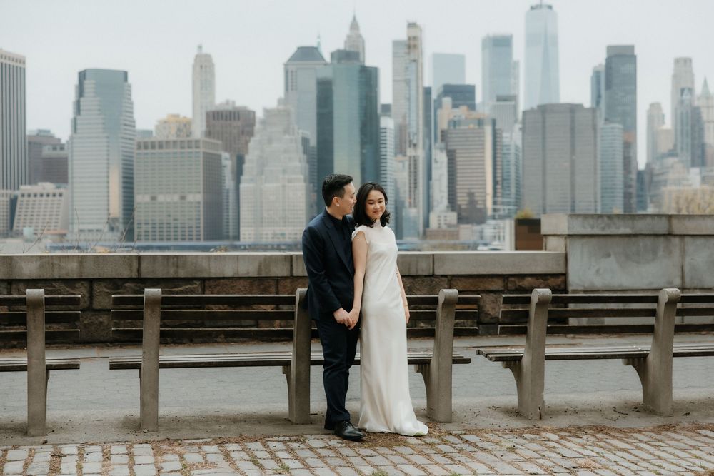 Wedding couple poses against Manhattan skyline on a rooftop with iconic skyscrapers in the background.