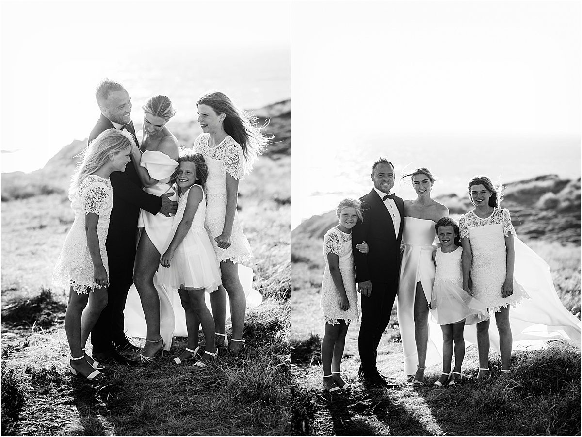 A wedding party gathered on a scenic coastal hillside for group photos.