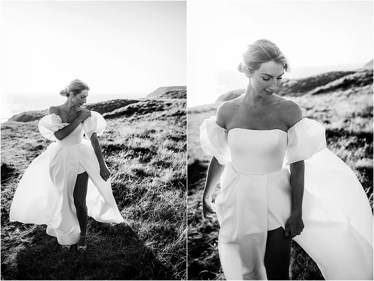 Dramatic black and white photos of bride in flowing dress moving along coastal hillside.
