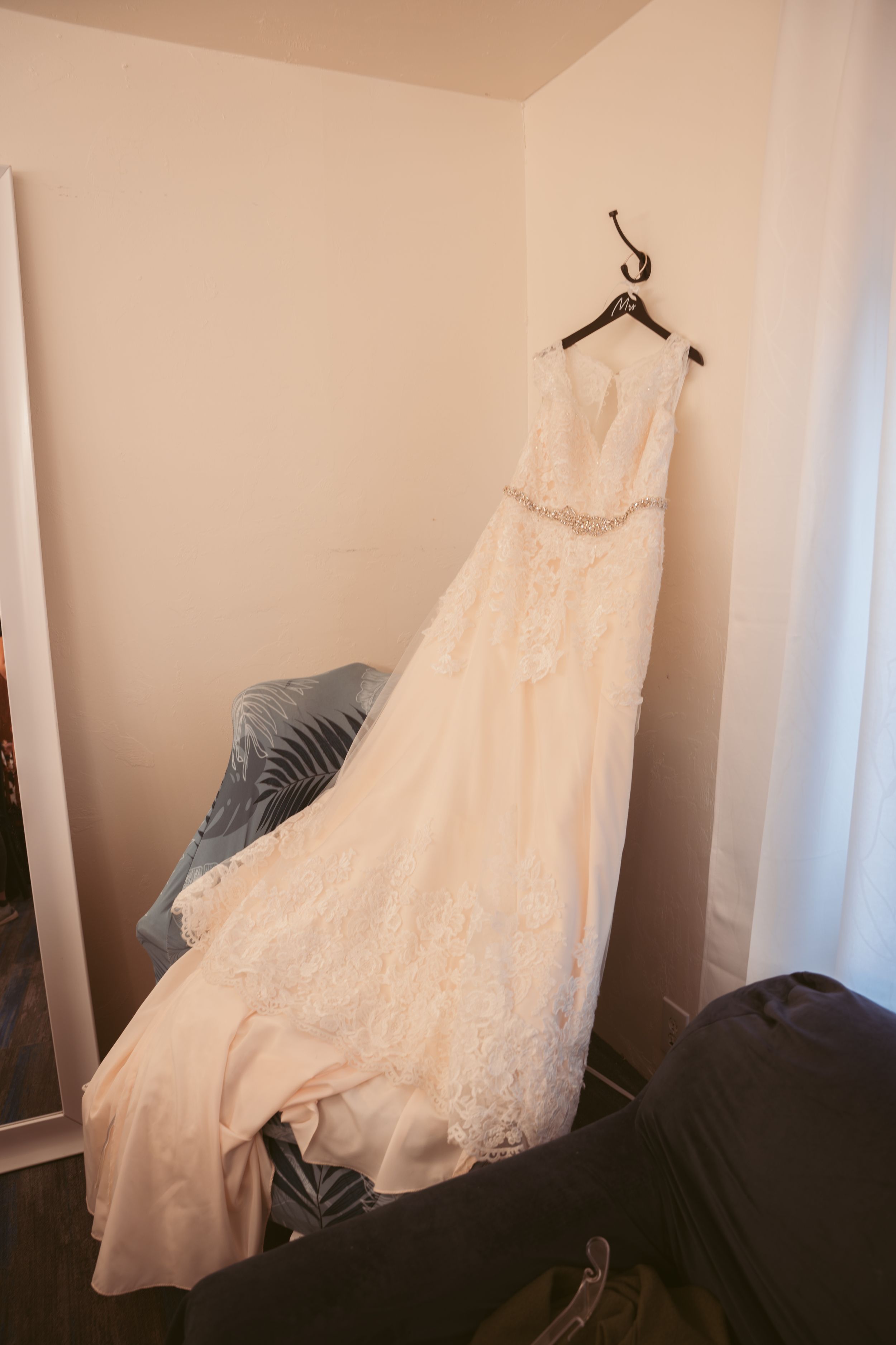A white lace wedding dress hangs gracefully across multiple frames showing different angles of its elegant silhouette.