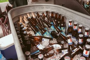 Ice-filled cooler with assorted beer bottles chilling at an outdoor event.