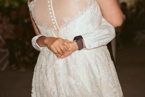 Detail shot of a white lace wedding dress with buttons and Apple Watch accessory.
