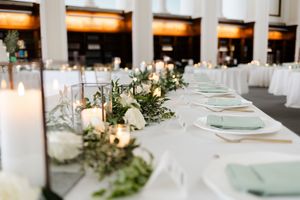 Elegant wedding reception table settings with seafoam green plates and delicate floral greenery garland decorations.