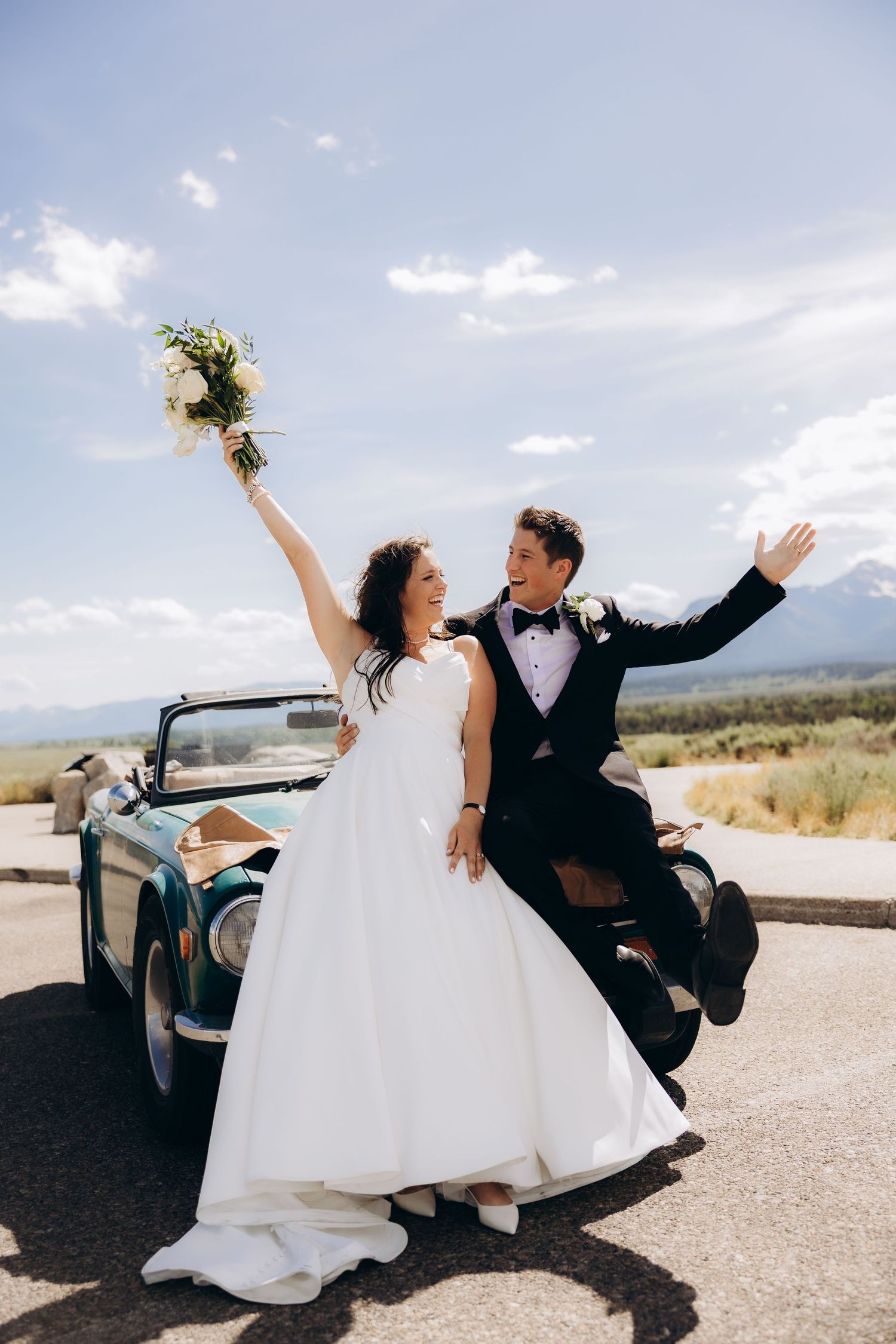 Joyful wedding sequence showing newlyweds posing playfully on a country road with classic car.