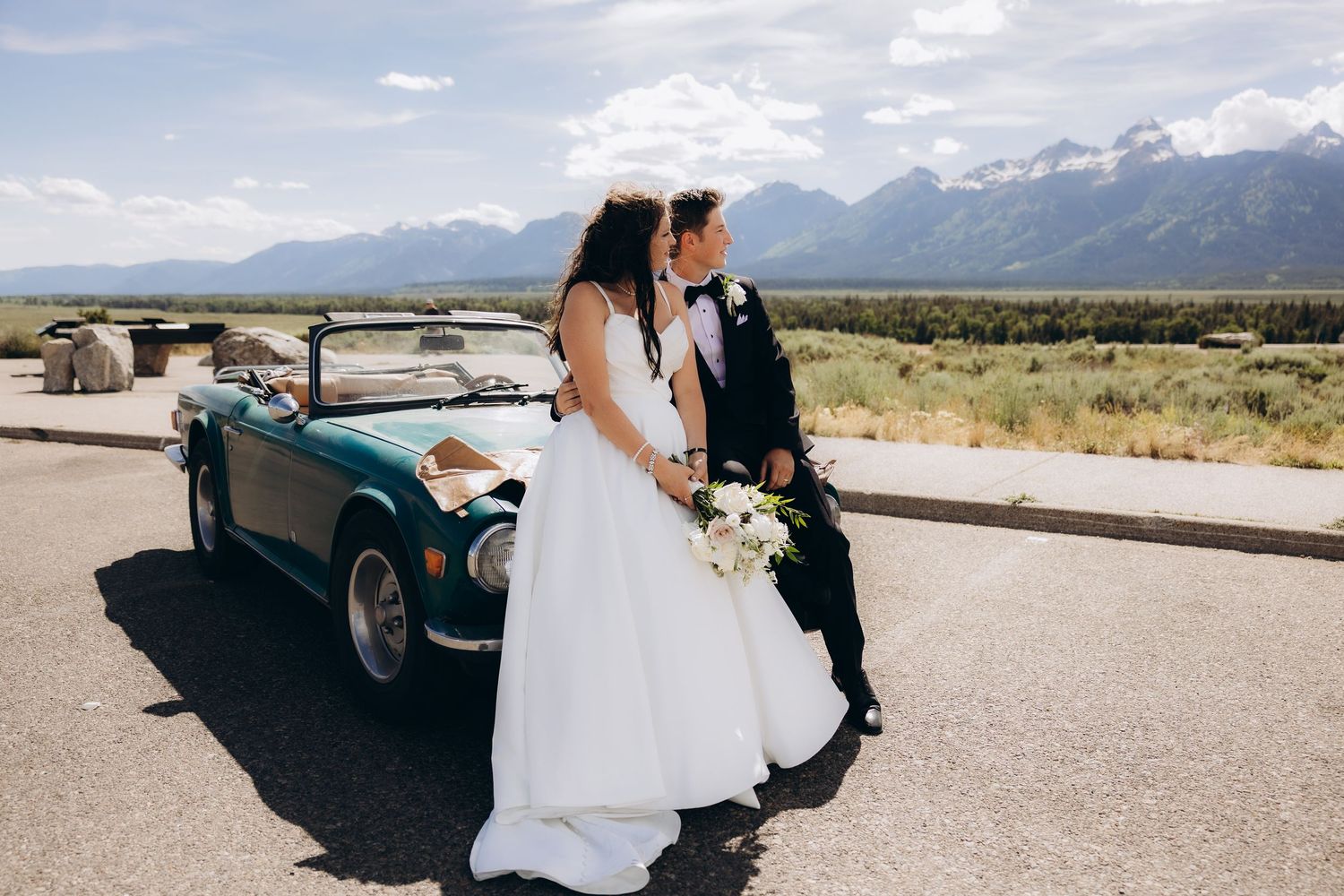 Vintage car with mountains in Wyoming on a scenic road with desert landscape and sage brush in the background.