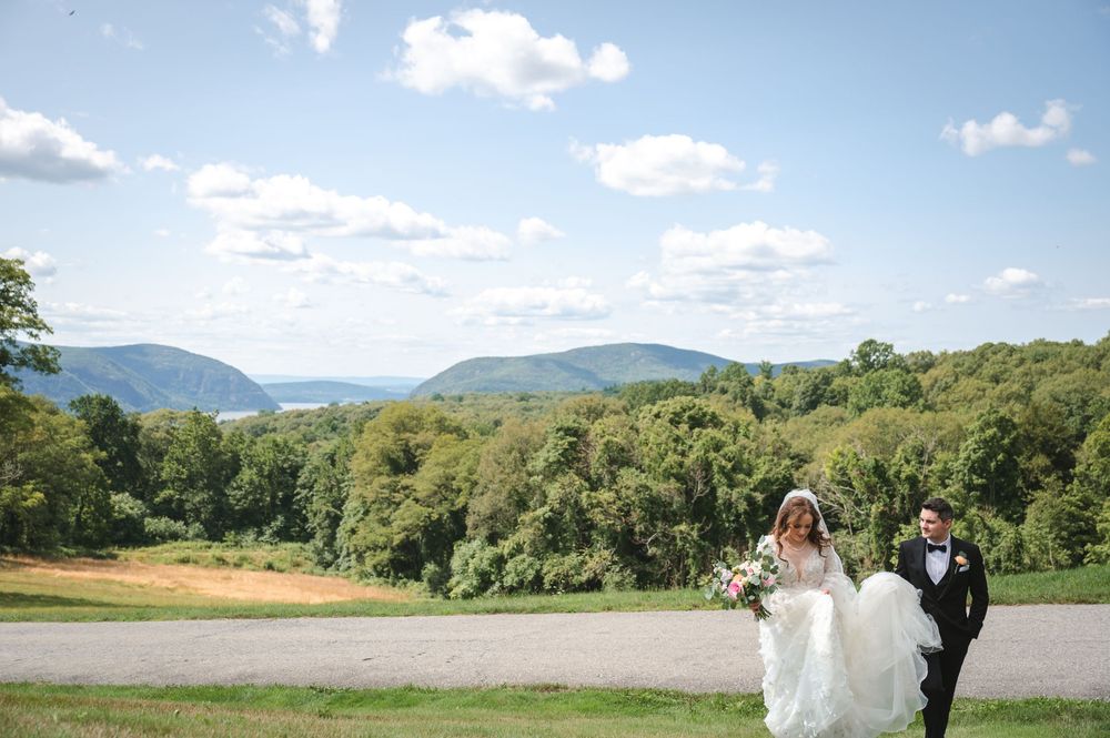 Scenic panoramic view of mountain ranges and rolling green hills under a bright blue sky with scattered clouds in Vermont.