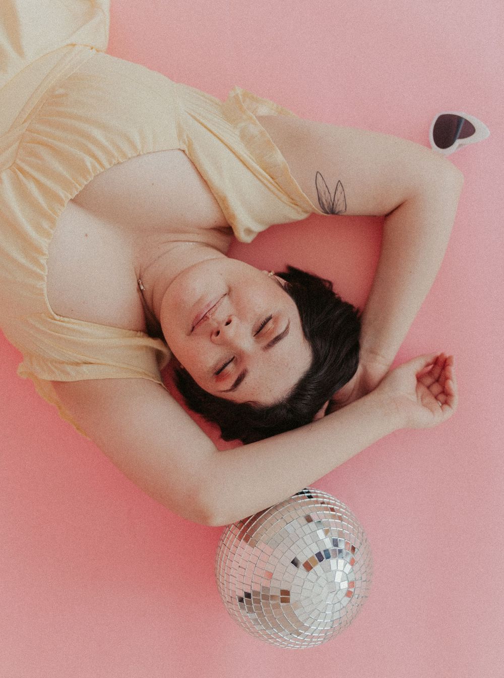 Colorful studio portrait of woman with disco ball on soft pink backdrop