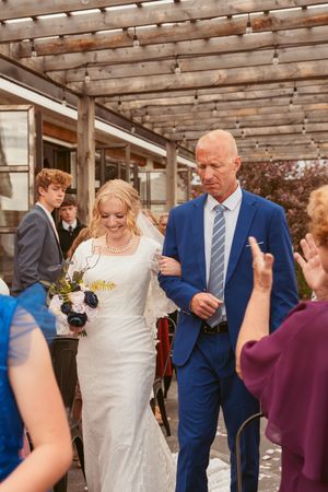 Wedding couple joyfully dances with guests during the reception under a wooden ceiling.