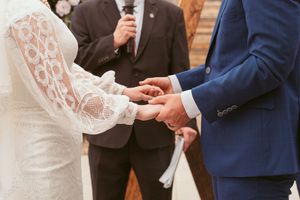 A close up of hands exchanging wedding rings during a marriage ceremony.
