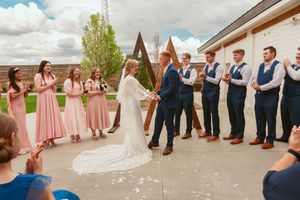 Wedding party members in pink dresses and blue suits dance and celebrate during an outdoor celebration.