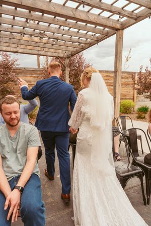 Three sequential images showing a person fixing a wedding dress under a wooden pergola on an outdoor patio.