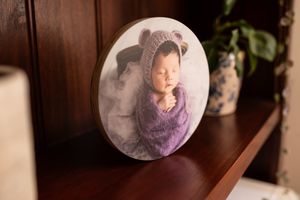 Round photographic print displayed on wooden shelf with decorative elements.