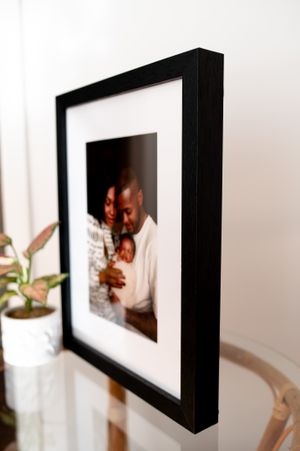 Black framed photograph displayed at an angle with houseplant in background.