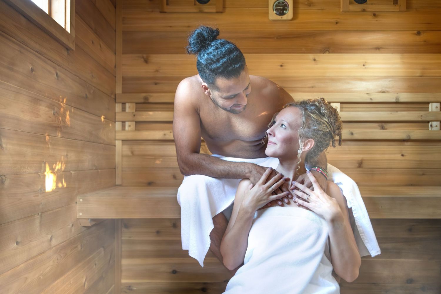 Couple sitting in sauna wrapped in towels, sharing warm intimate moment - Okanagan lifestyle branding photography by Tania Veitch.