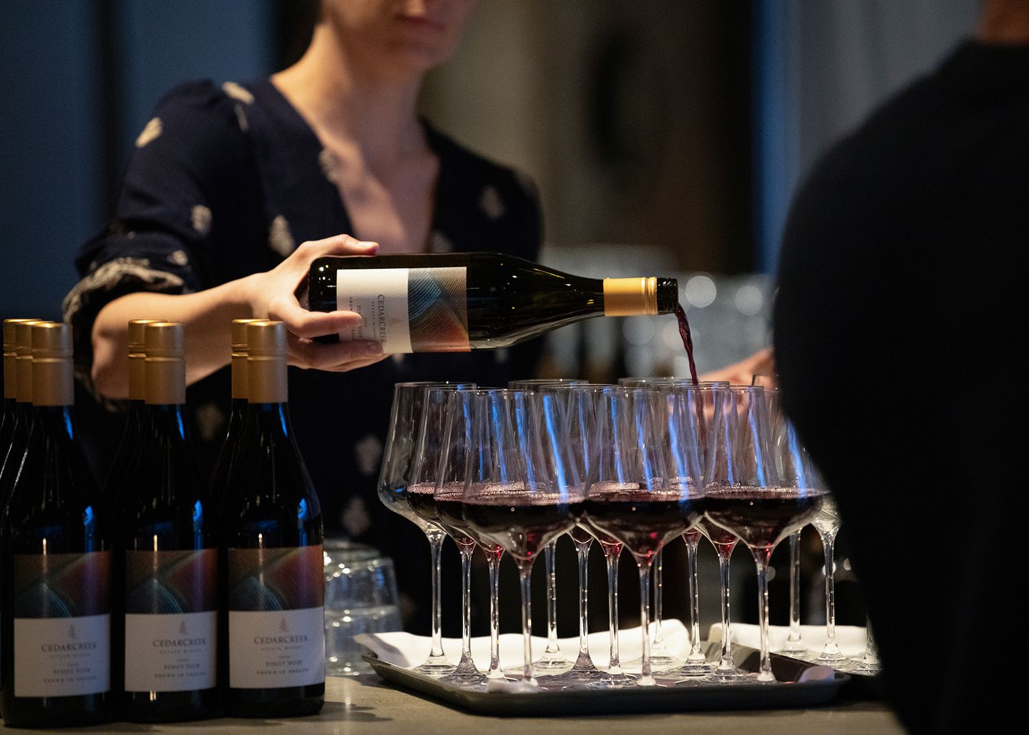 Event wine service with server pouring red wine into glasses at an Okanagan hospitality event.
