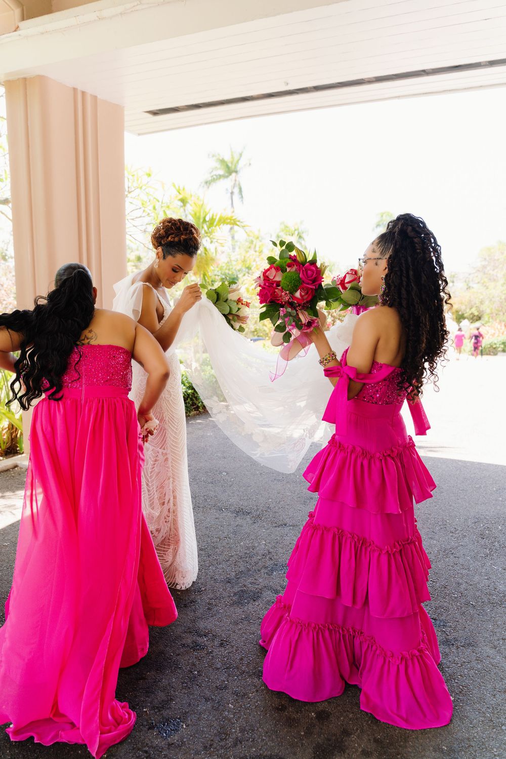 Wedding party candid shots showing bridesmaids in vibrant hot pink dresses dancing and twirling with the bride in white.