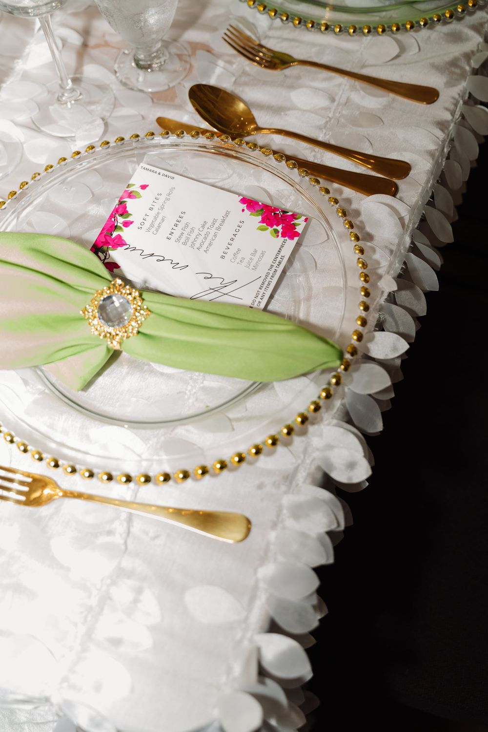 Elegant place setting with gold-rimmed plate, green ribbon, and white linens decorated for a formal dinner event.