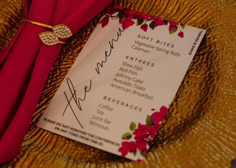 Close-up of wedding invitations with pink floral design elements on textured gold background.