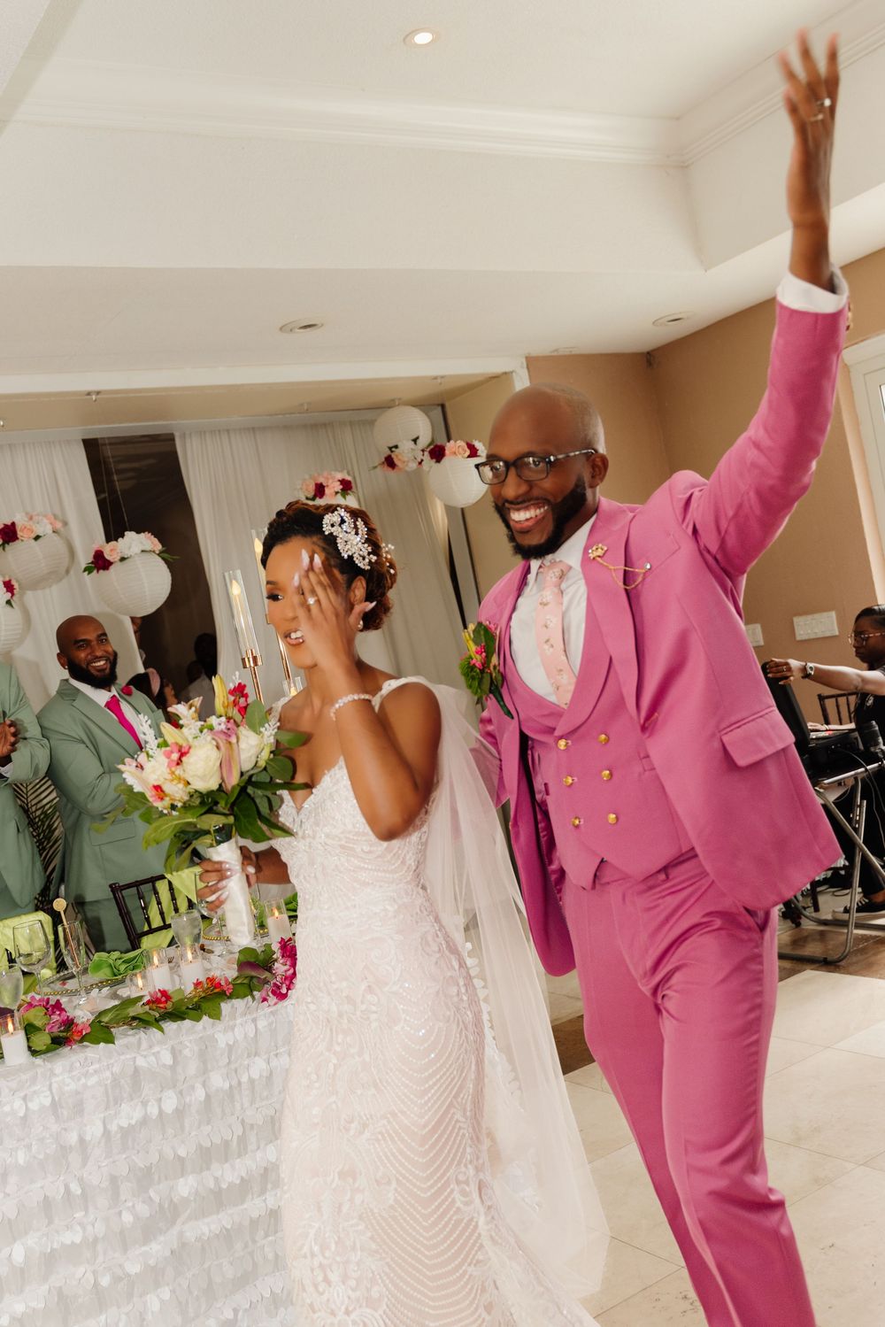 Wedding celebration in a banquet hall with pink and white decor and celebratory dancing.
