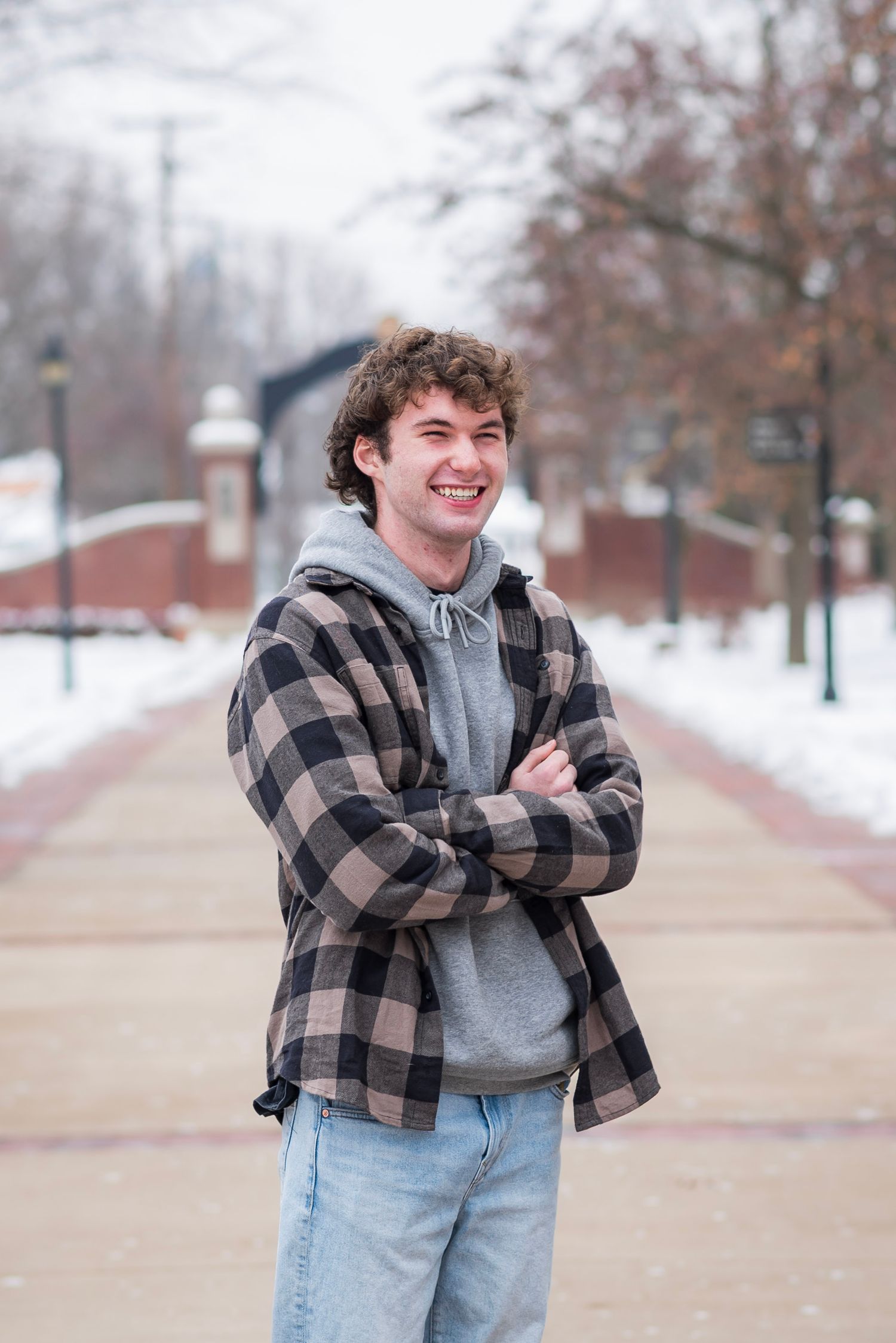 Person wearing buffalo plaid jacket and jeans poses confidently in winter setting.