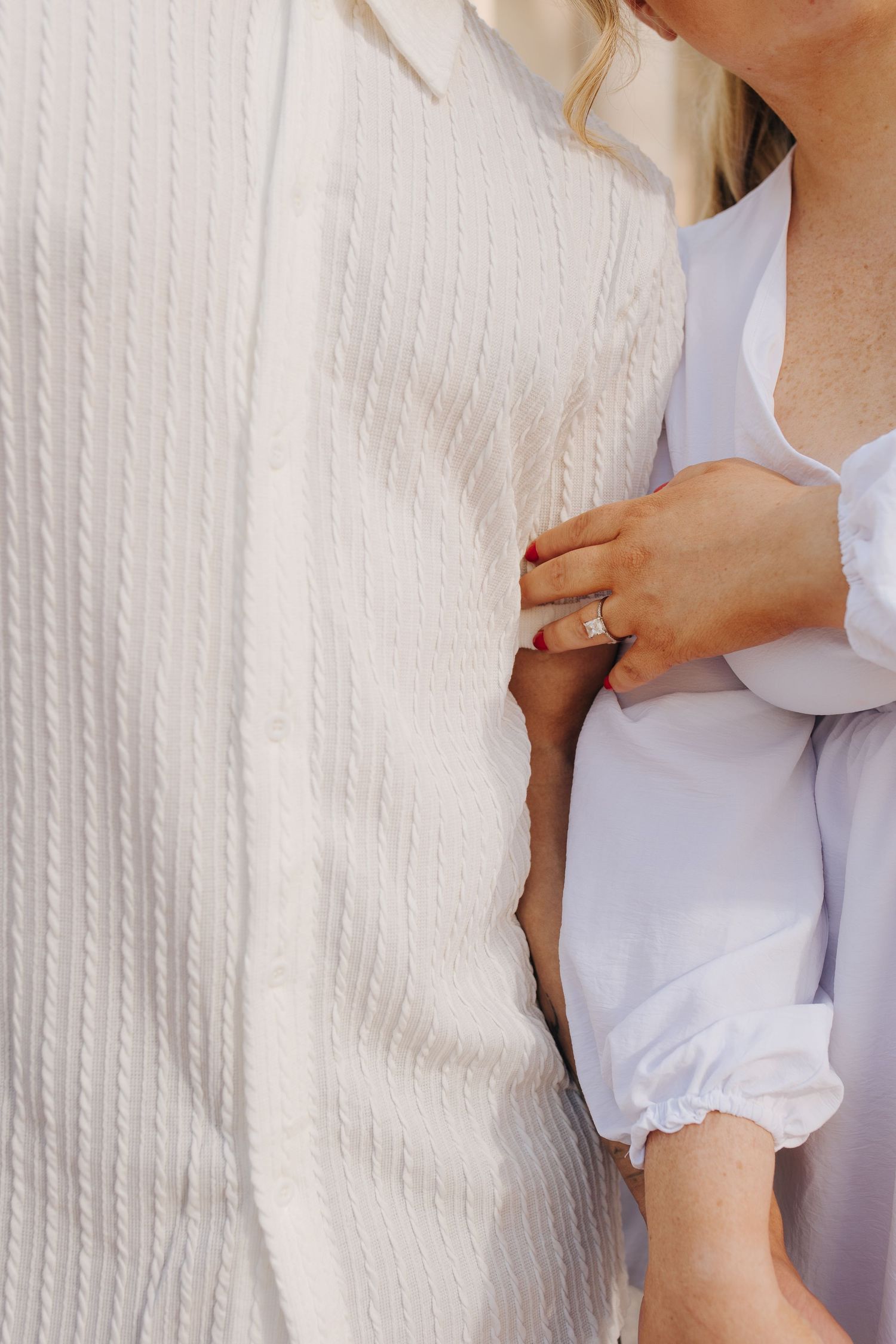 Detail shot of engagement ring as couple holds hands and leans into each other at Ohio Statehouse.