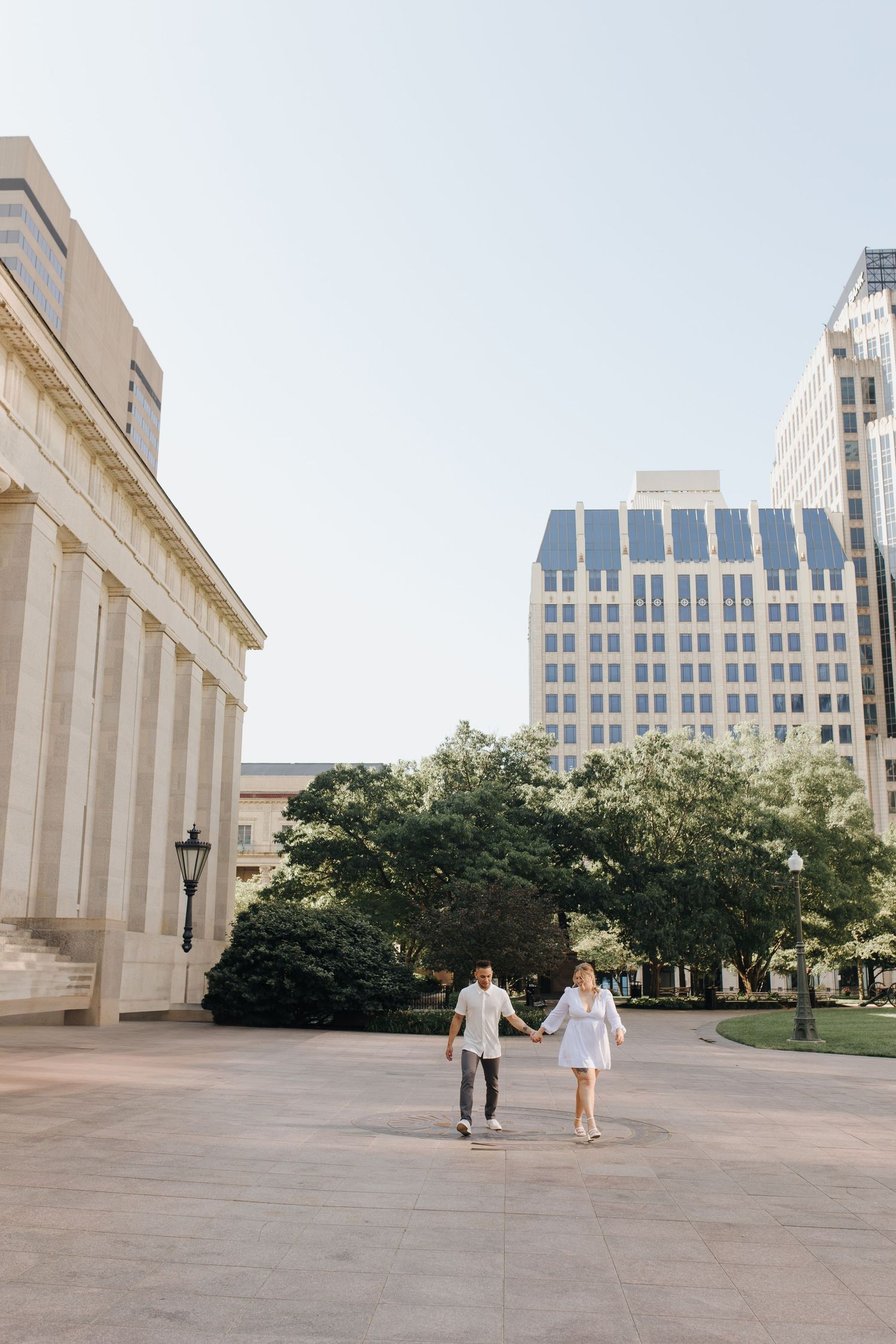 Wide shot of couple walking happily in front of the Ohio Statehouse in Columbus, Ohio.