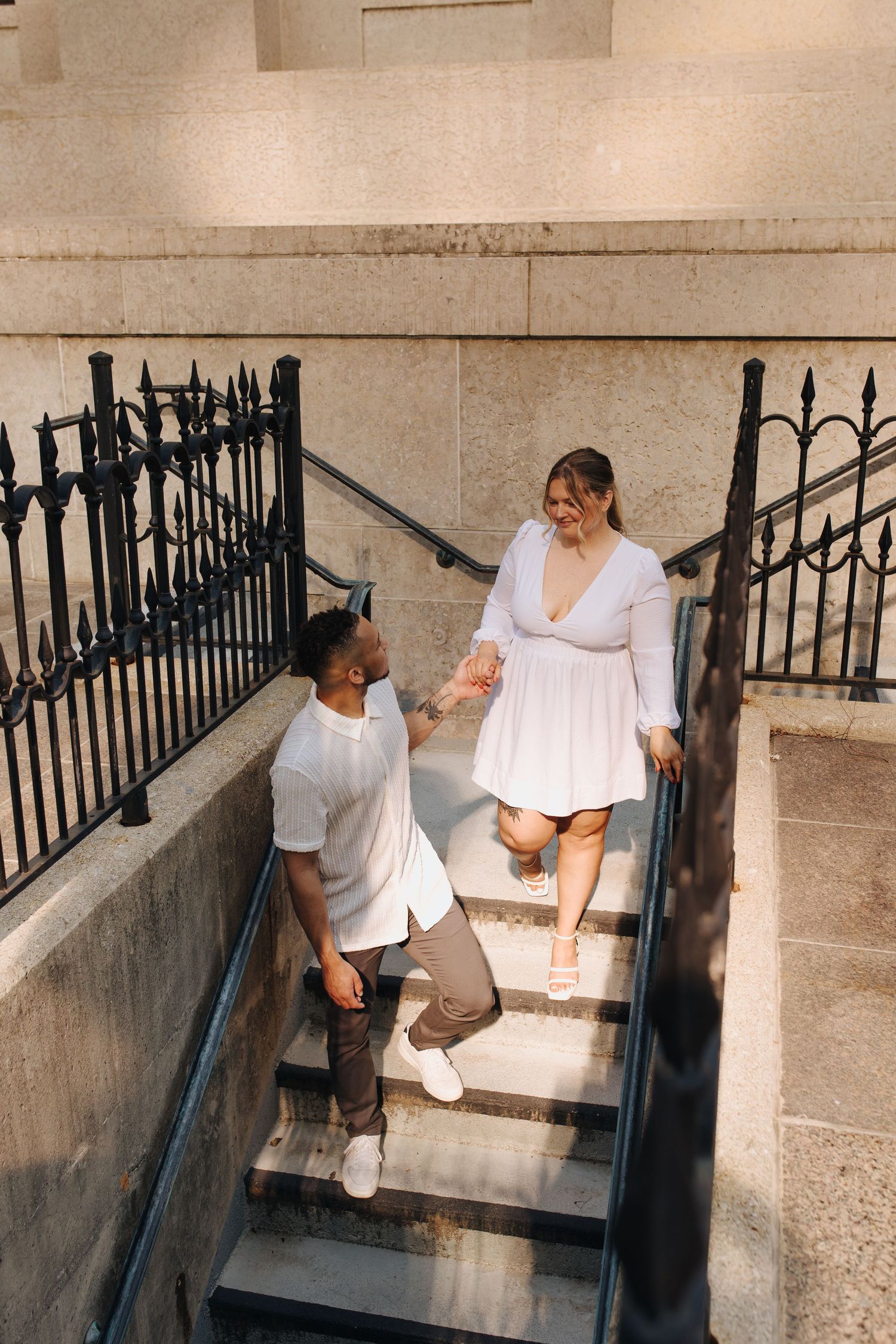 Candid moment of couple walking down the stairs with soft golden light in downtown Columbus.