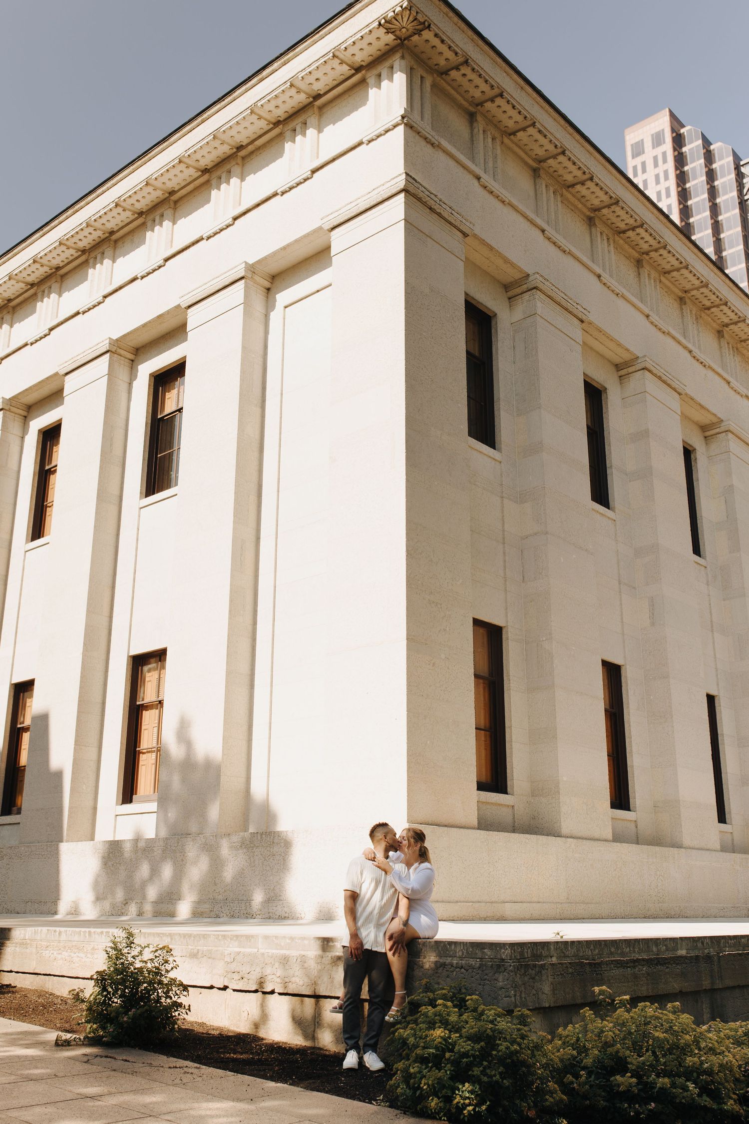 Intimate photo during engagement session with warm golden light and classic architecture backdrop.