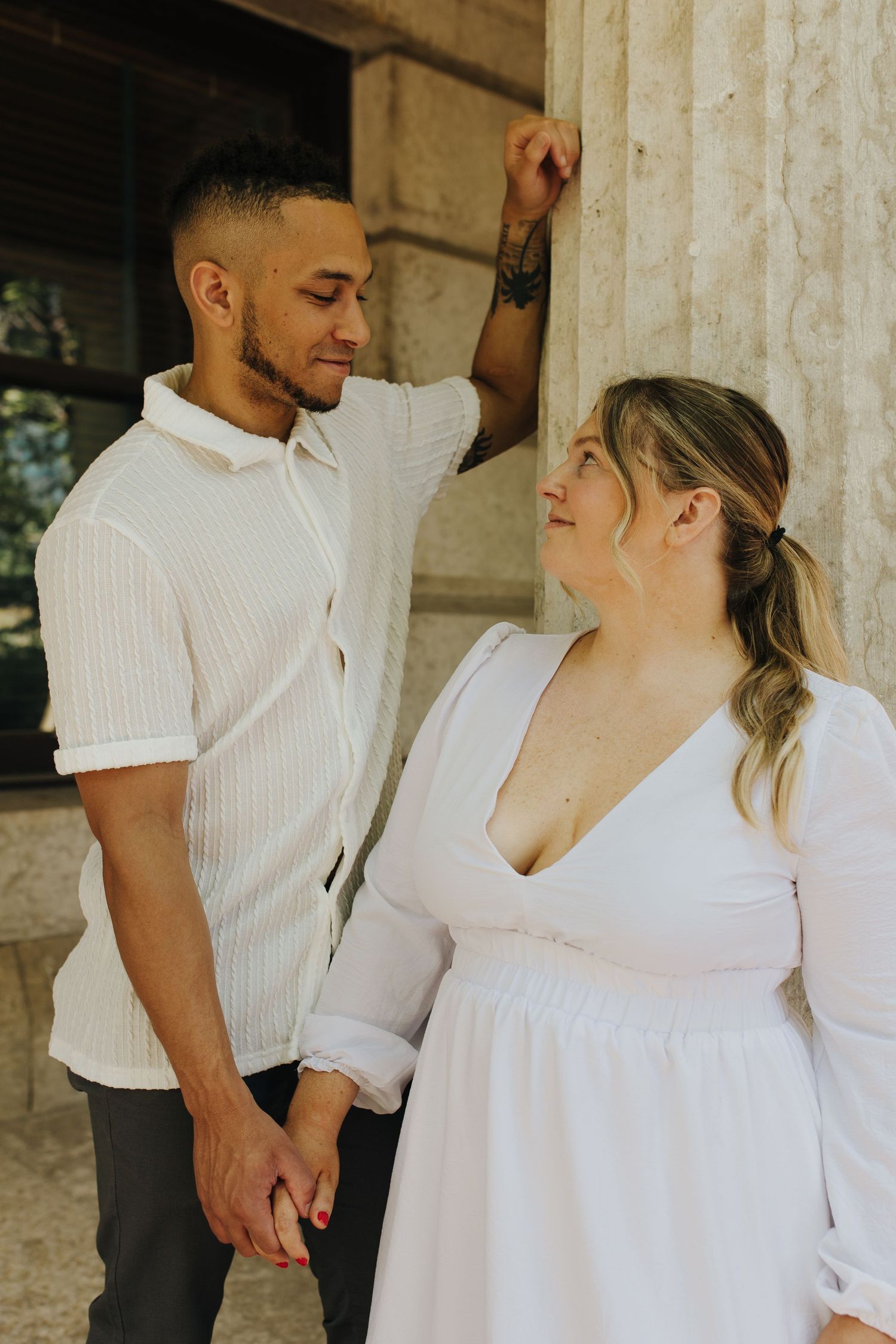 Elegant engagement portrait of couple standing against the Ohio Statehouse pillars, hand in hand.