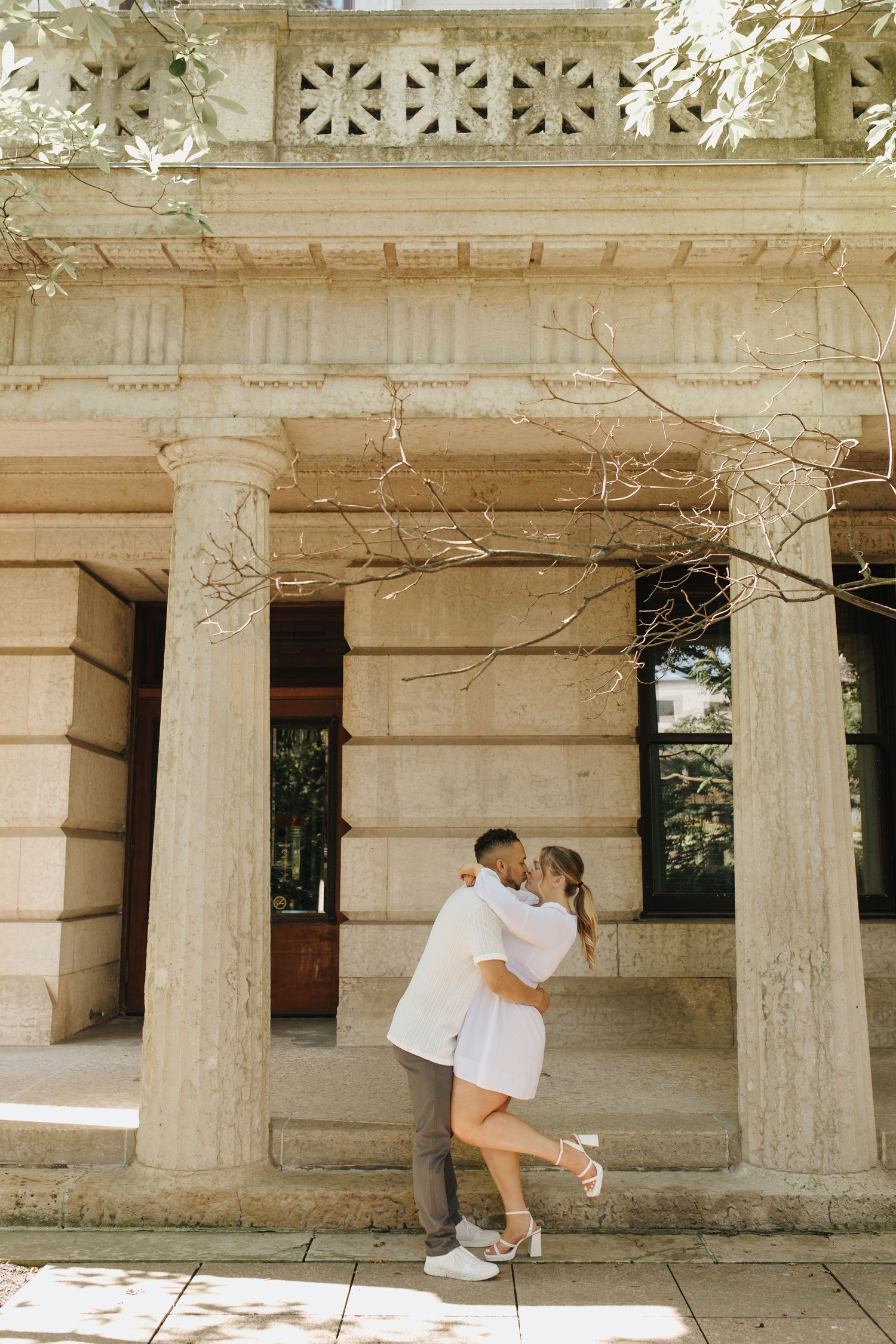 Columbus engagement session with couple embracing in front of neoclassical columns at the Statehouse.