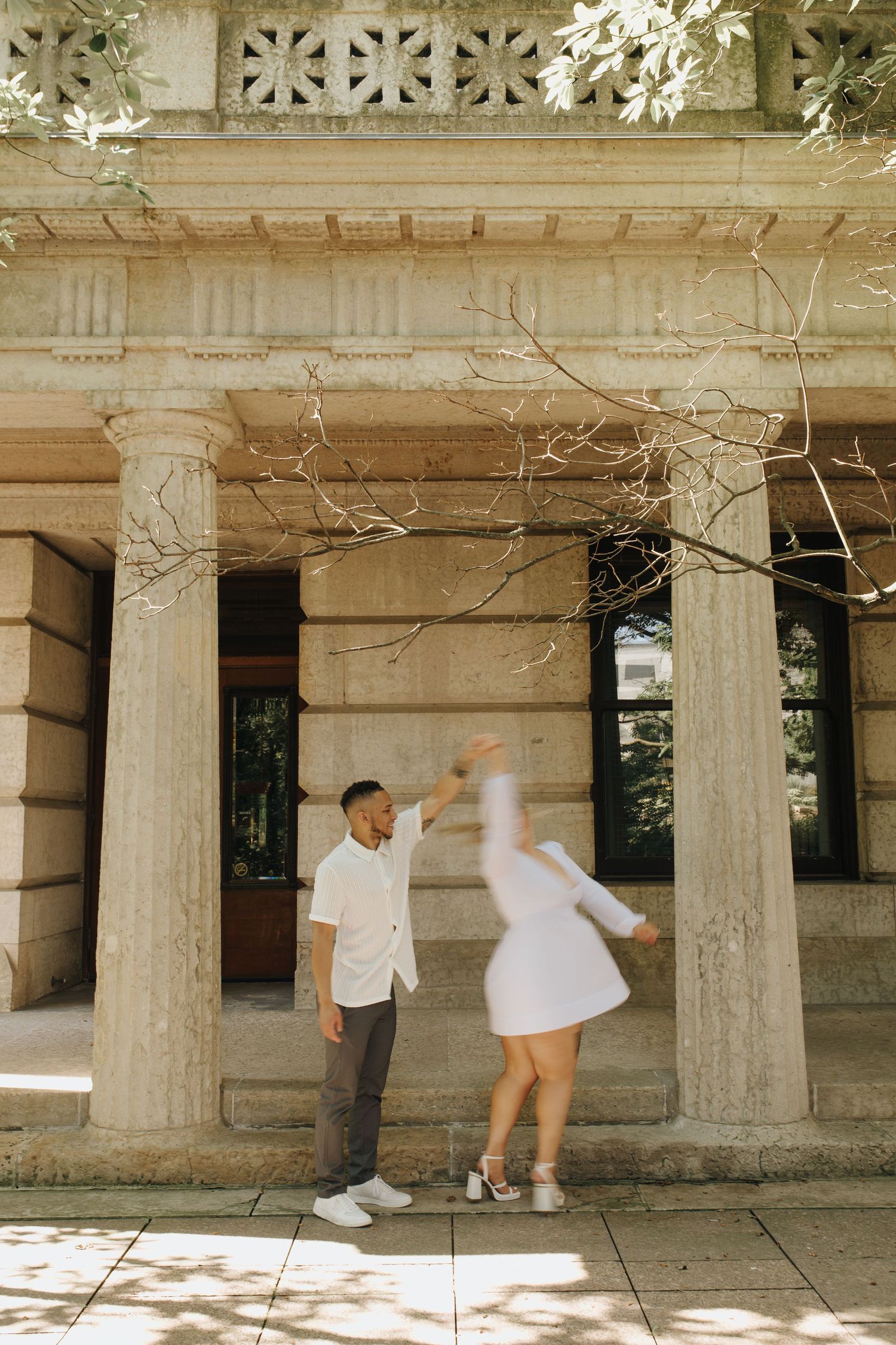 Romantic twirl during engagement session with classic column backdrop in downtown Columbus.