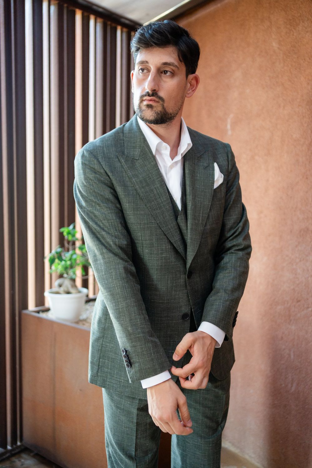 A series of photos showing someone in a grey suit posing against a brown wall.