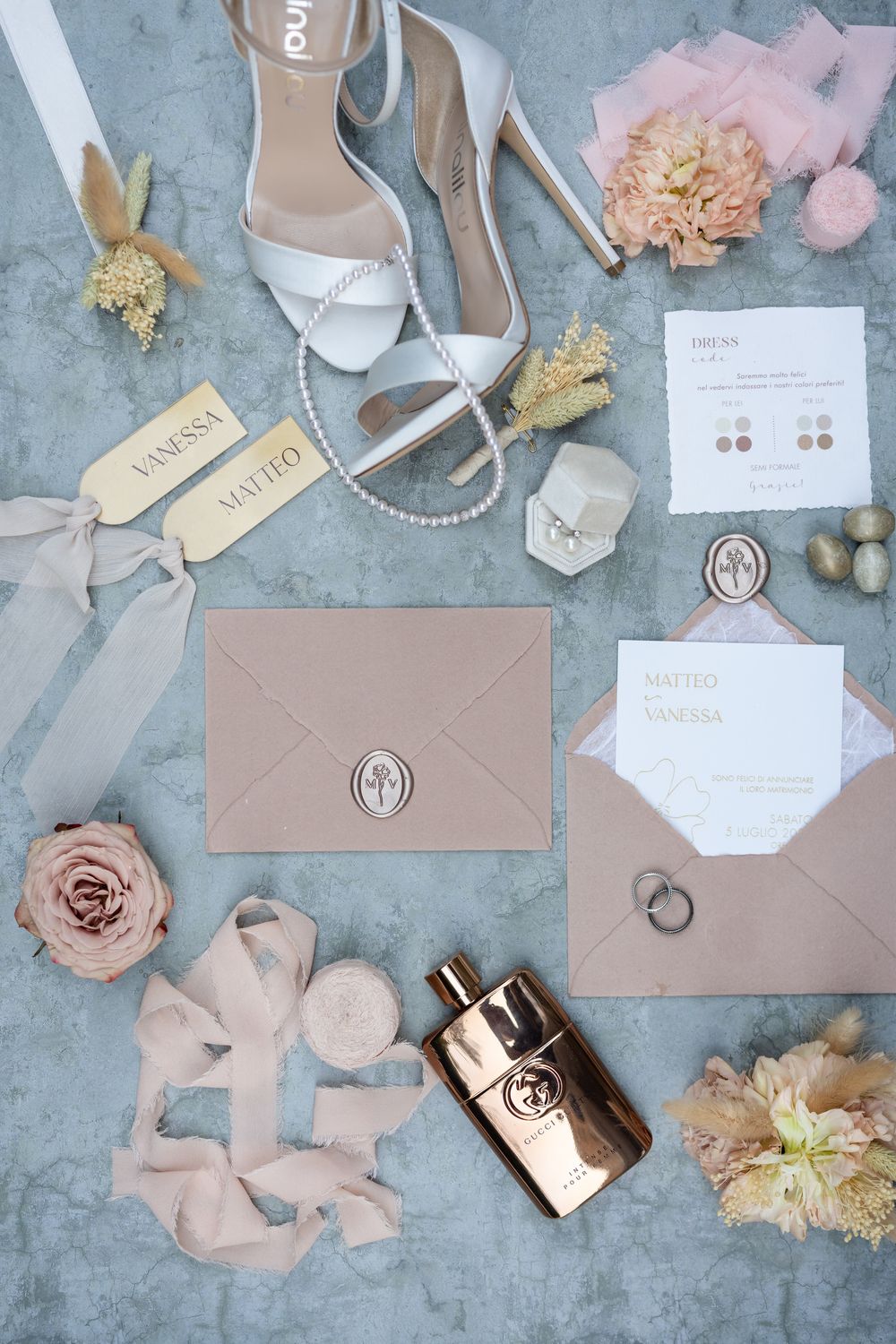Wedding accessories flatlay featuring invitations, shoes, and jewelry in blush pink and white tones.