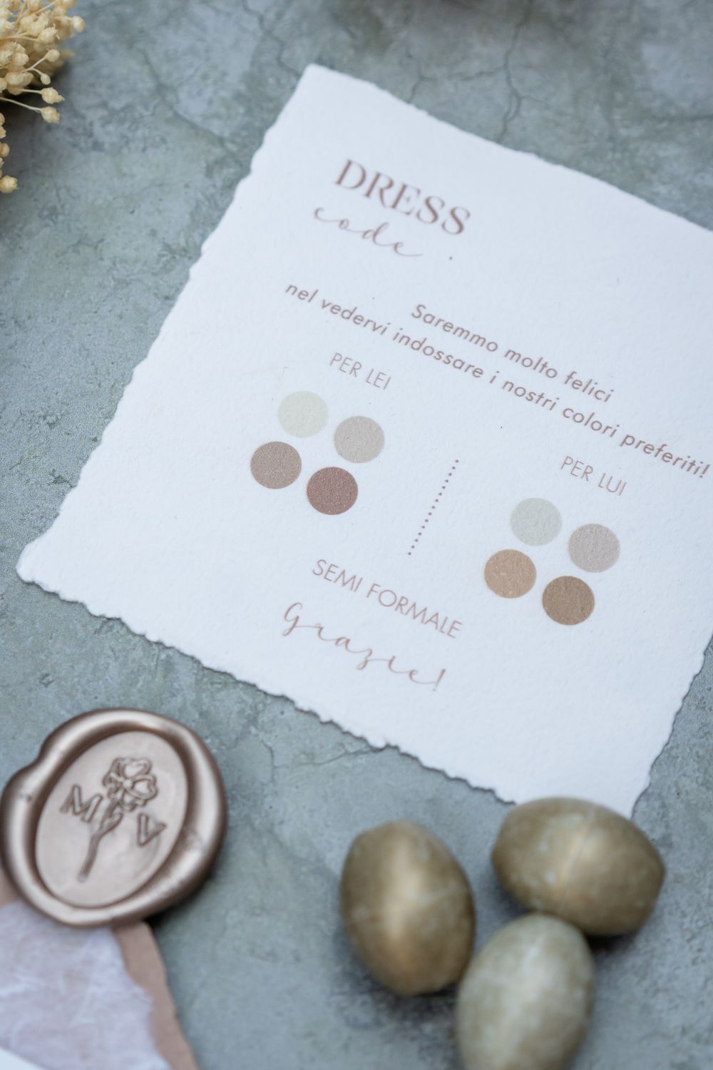 Wedding color palette card with neutral tones and wax seals on a textured gray surface.